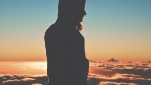 A woman on high mountain with clouds behind her.