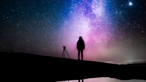 Silhouette of a person with a telescope against a gorgeous starry sky