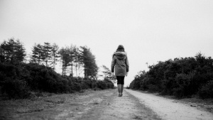 A woman walking on a dirt road.