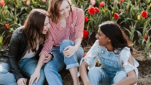 Group of three girl friends sitting together, smiling and enjoying each other's company.