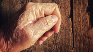 An old hand knocking on a old wooden door.