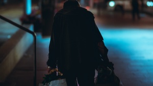 Homeless man walking down street at night under street lights
