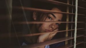 A sad looking woman gazing out a window.