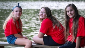 three girls sitting on a bench by the lake