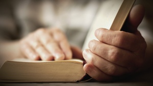 A pair of hands holding an open Bible