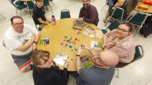 six people gathered around a table playing games