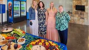 four ladies gathered by a table of colorful food