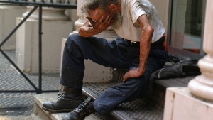 a man sitting outside with his head in his hand