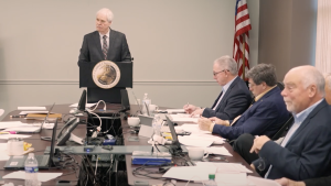 several of the council members sitting around table and listening to a speaker