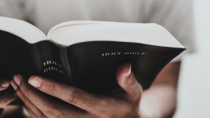 An upclose photo of a man's hands holding a Bible.