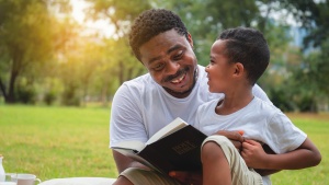 A dad talking to his son while holding a Bible.