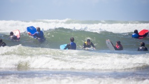 a group of teenagers with boogie boards among the waves