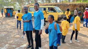 a group of children and teenagers standing outside in front of a bus