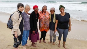 six women standing on the beach