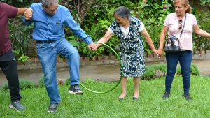 three people standing outdoors participating in a team activity with a hula hoop