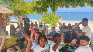 a group of people sitting at tables outdoors with the ocean in the background