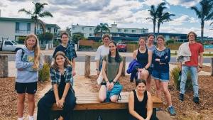 a group of teenagers standing and sitting outdoors in front of some buildings