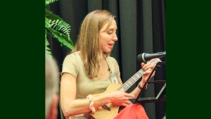 a woman playing a ukulele onstage with a microphone