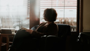 A woman sitting in a chair looking at a book.