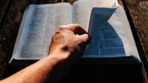 A man turning pages of a Bible.