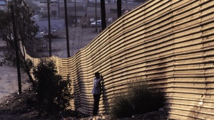 People standing by a border wall.