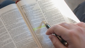 A photo of a hand highlighting a scripture in the Bible. 