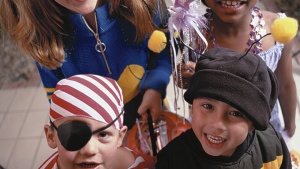 Little kids in costumes trick-or-treating at a house.