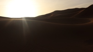 Desert mountains with the bright sun in the distance.