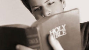 A teen boy looking at a Bible.