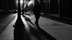 A person walking on a sidewalk at night.