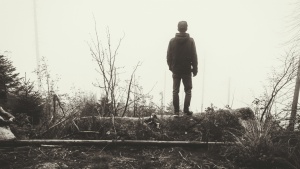 A young man walking in a foggy forest.