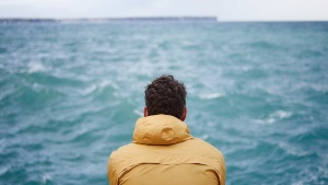 A man watching the waves on a lake.