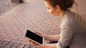 A young woman reading on a tablet device.