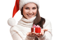 A woman wear a Christmas stocking cap holding a gift.