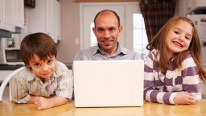 A dad sitting with two kids at a table.