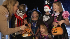 Little children dressed up in Halloween costumes trick or treating.