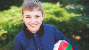 A young boy holding a ball and smiling.