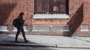 A woman walking by an old brick building.