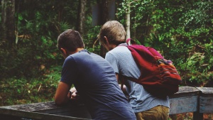 Two young boys together hiking in the woods.