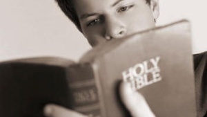 A teenage boy reading the Holy Bible.