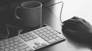 A person&#039;s hand on top of a computer mouse ready to click.