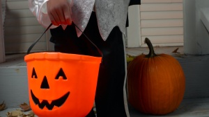 A child carry a jack-o-lantern bucket for candy.