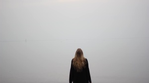 A woman standing by herself looking up.