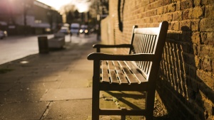 A empty bench on a sidewalk.