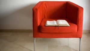 Bible laying in an empty red chair.