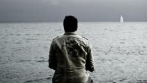 A man sitting on a rock looking at water.