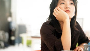 A woman with her head resting on her hand and looking thoughtfully.