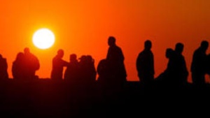 A group of people watchingthe sunset.