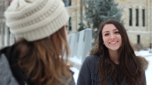 Two young adult women talking to each other while being outside in the cold.