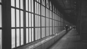 A long hall lined by windows with people walking in the distance.